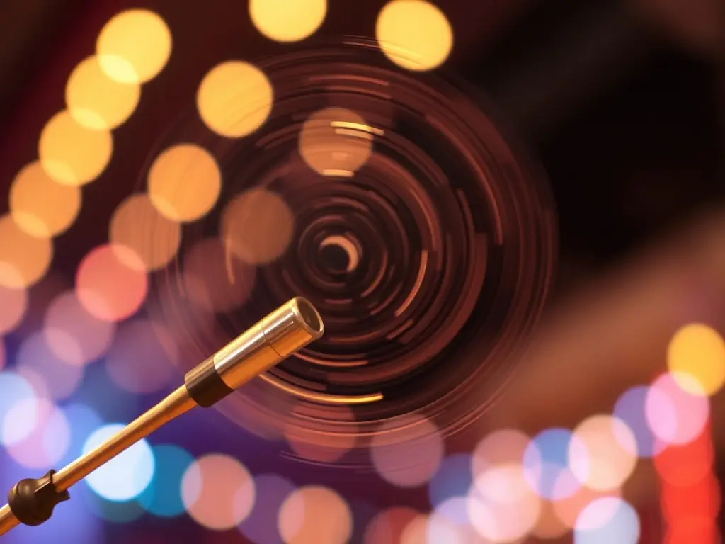 A close-up shot of a twirling baton in motion, with blurred lights in the background, symbolizing the speed and skill involved in baton manipulation. The image conveys the excitement and challenge of twirling.